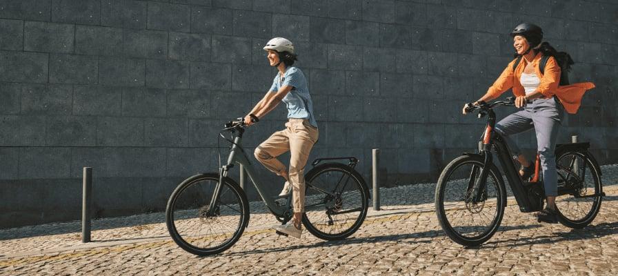 Zwei Personen fahren E-Bikes auf gepflastertem Weg in Wien