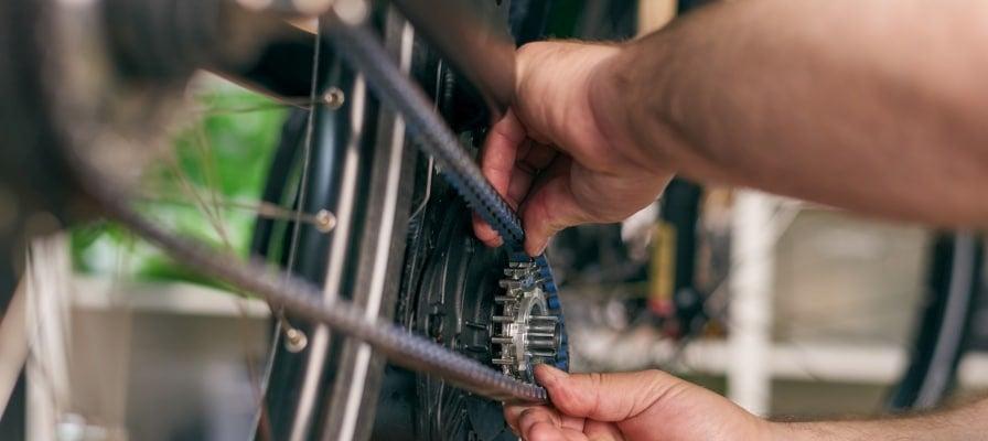 Fahrradmechaniker justiert Riemenantrieb an Hinterrad