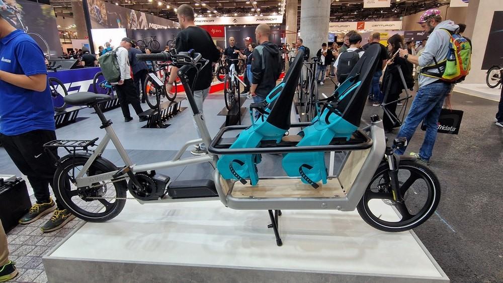 Johansson Lasten e-Bike mit Alurahmen und zwei blauen Kindersitzen, vereint robuste Bauweise und Familiennutzung