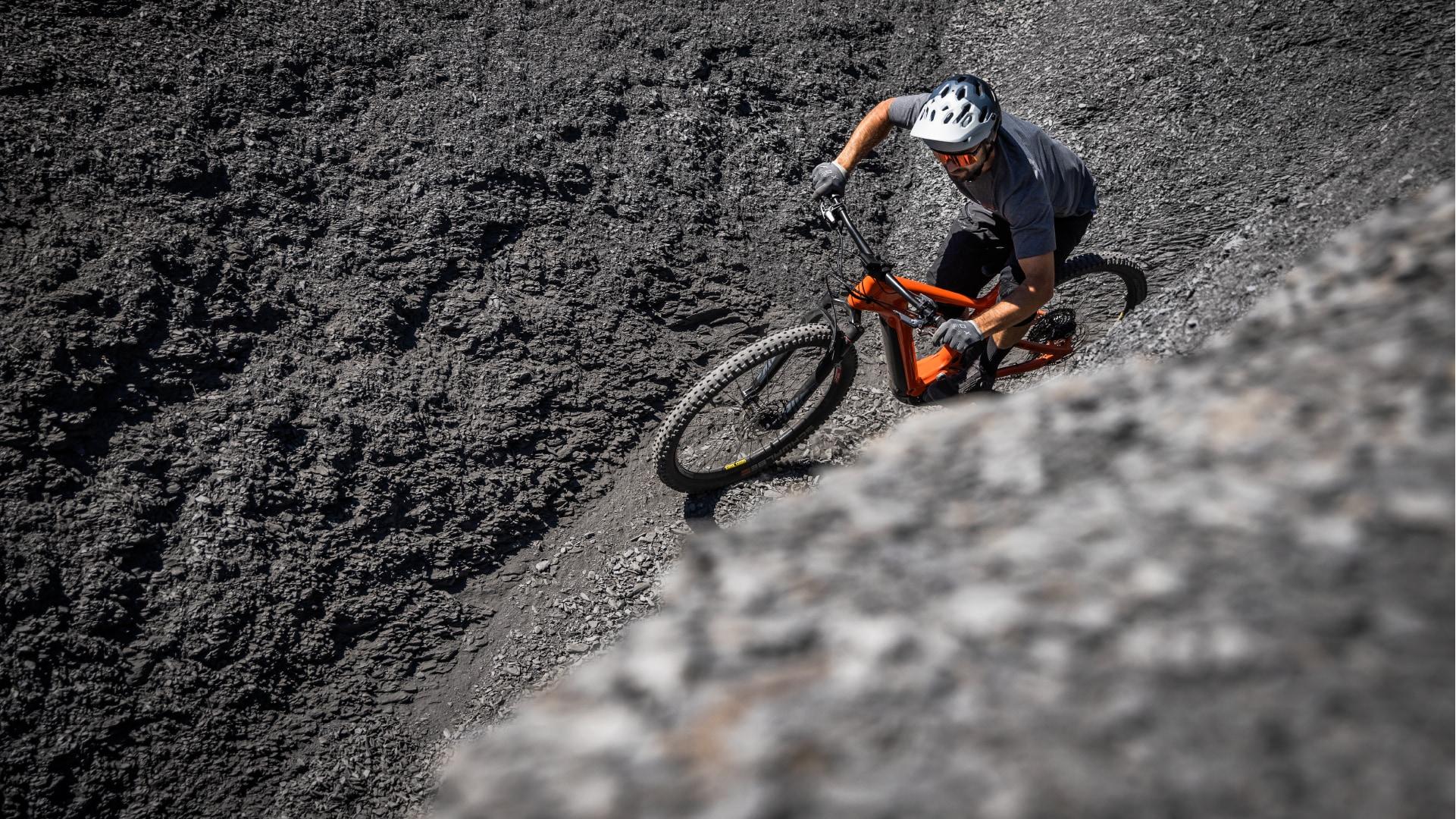 Ein e-Biker ist unterwegs auf sehr steinigem und hügeligem Untergrund