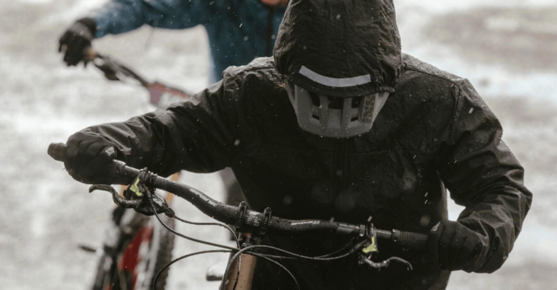 Person mit Kapuze schiebt e-Bike durch den Schnee mit Schiebehilfe