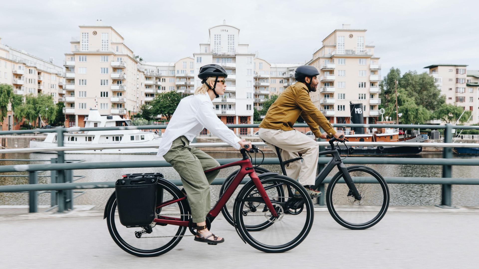 Zwei Personen auf Specialized Vado SL E-Bikes in der Stadt, perfekt für urbane Mobilität und stilvolles Pendeln.