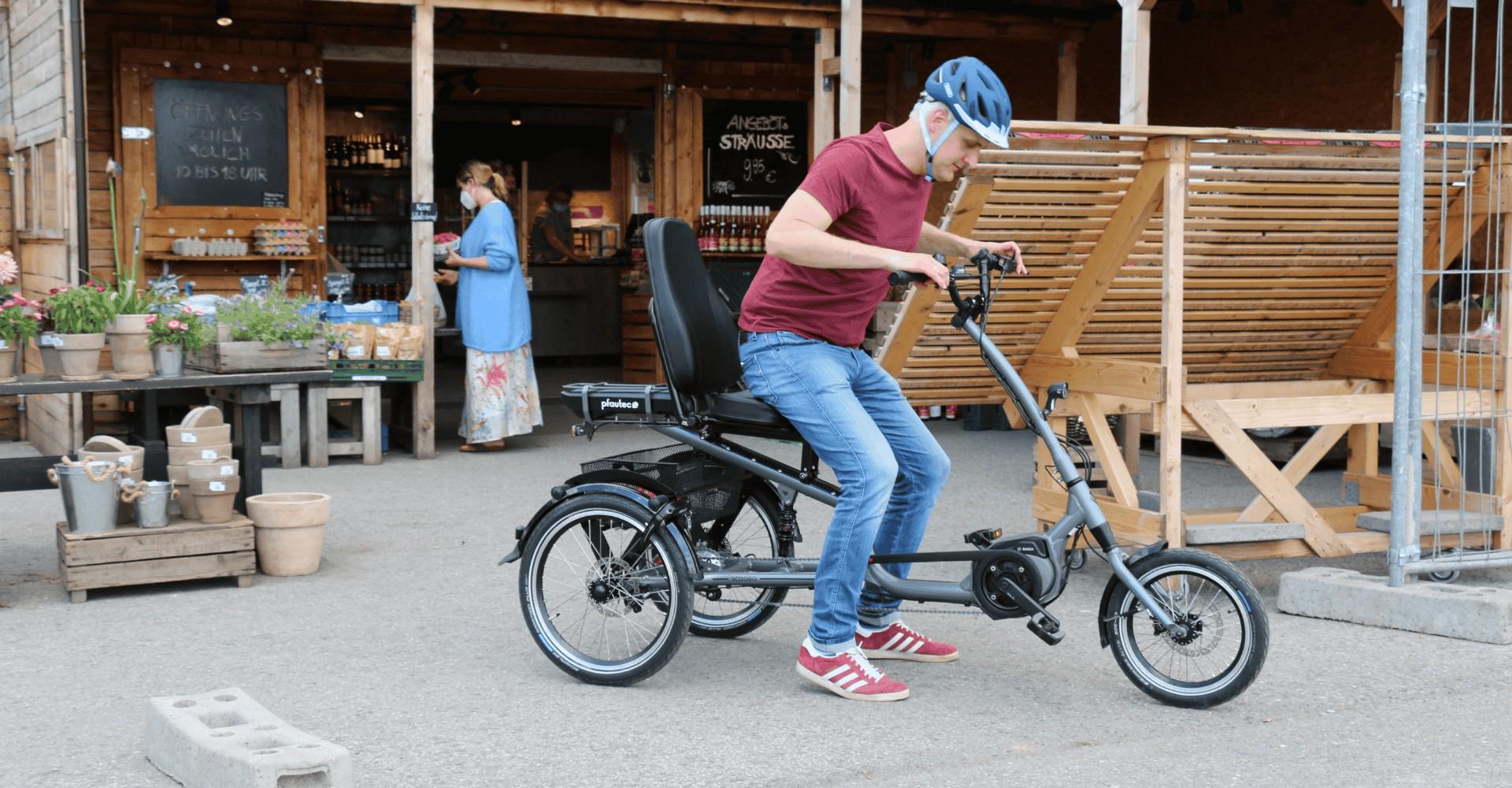 Ein Mann steht aus dem Dreirad Scoobo auf