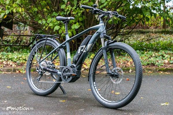 E-Bike auf nasser Straße vor grünen Büschen