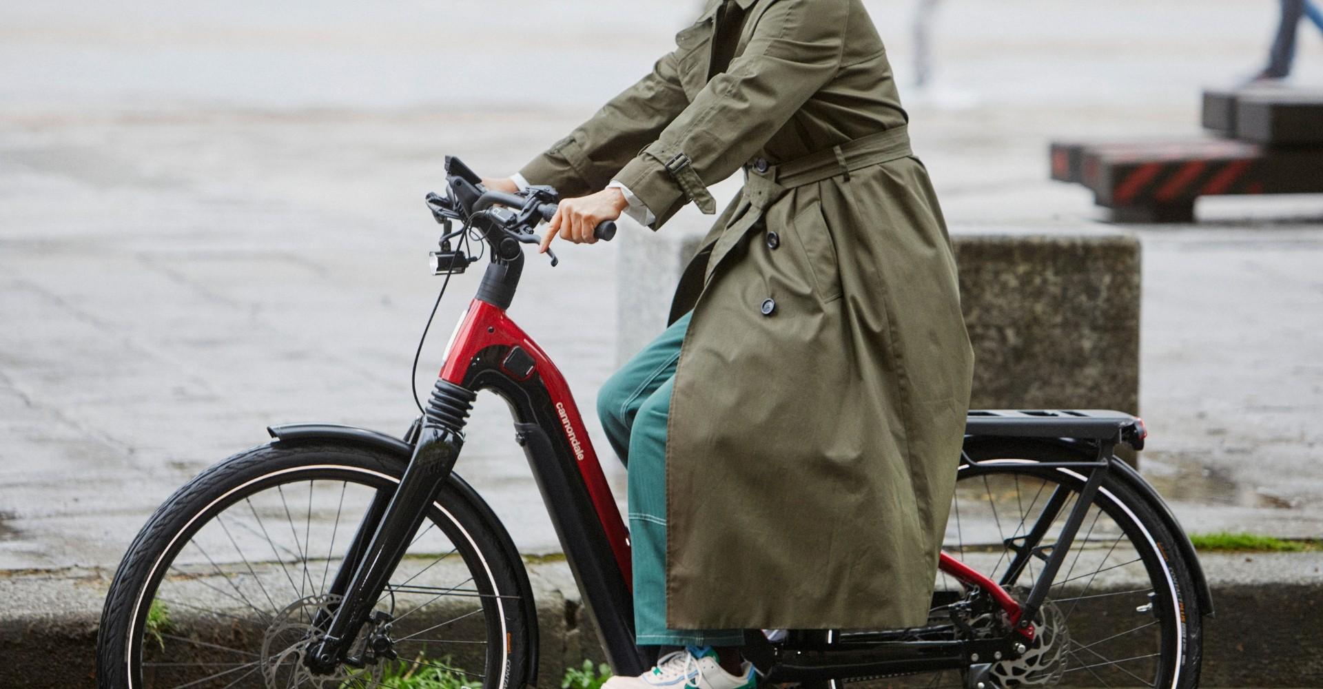 Eine Frau mit Mantel fährt auf dem Cannondale Mavaro Neo 2022