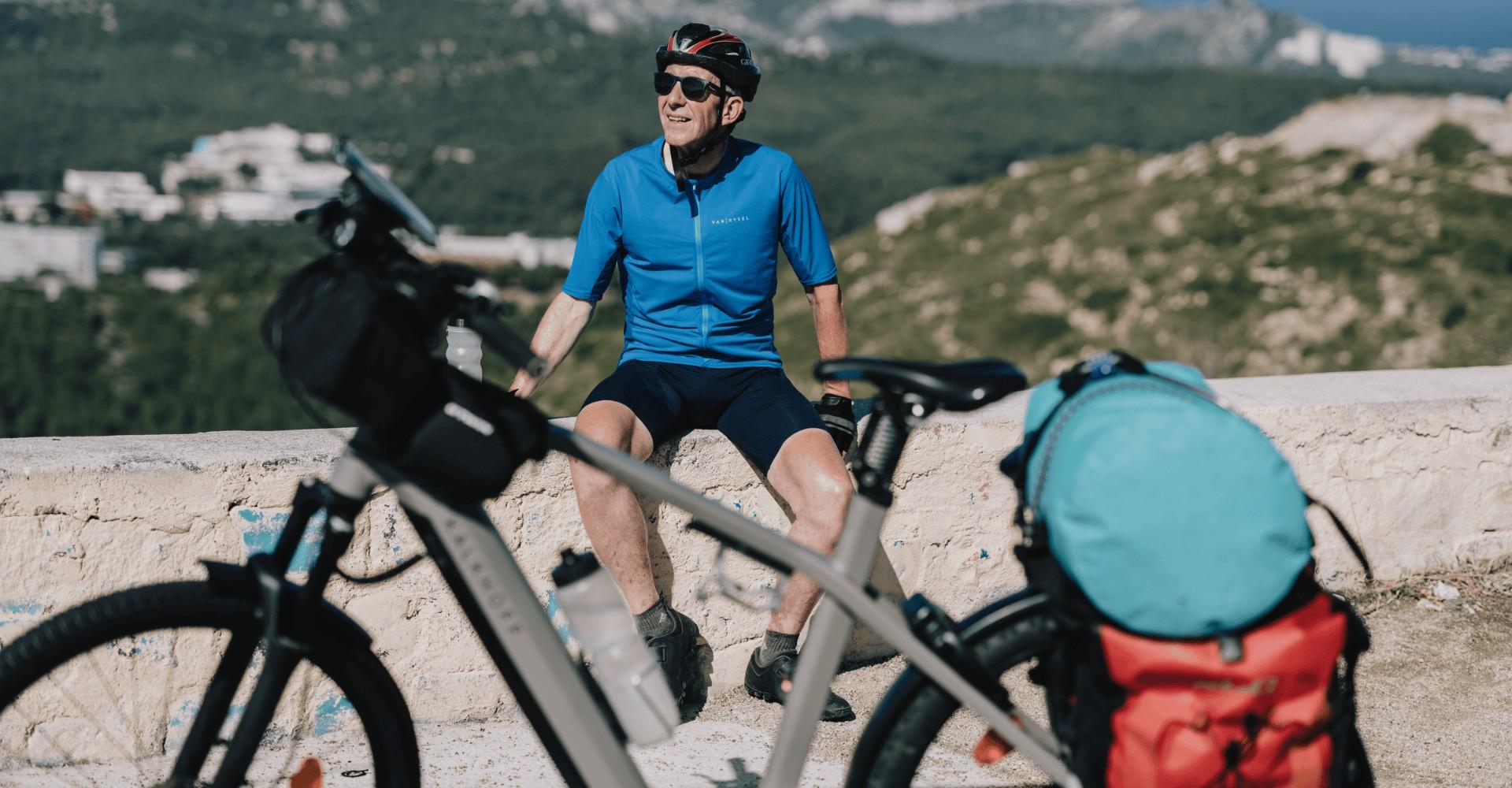 Ein Mann sitzt mit Helm vor seinem vollgepackten Kalkhoff e-Bike