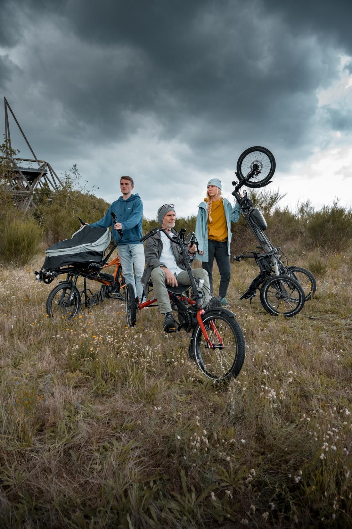 Drei Personen stehen auf einer Wiese mit verschiedenen hase bikes Modellen