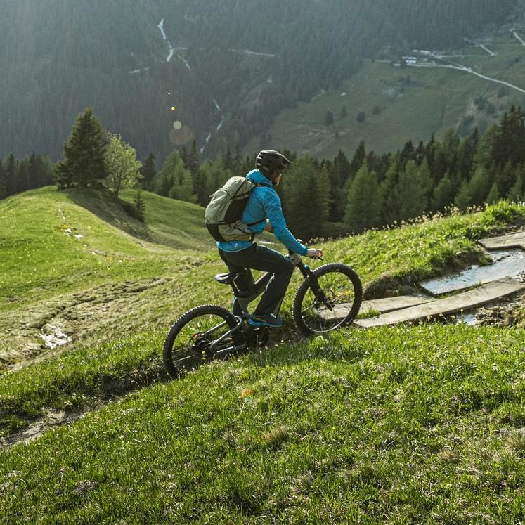 Eine Person fährt mit dem e-MTB Riese & Müller Superdelite durch das Grüne und die Berge