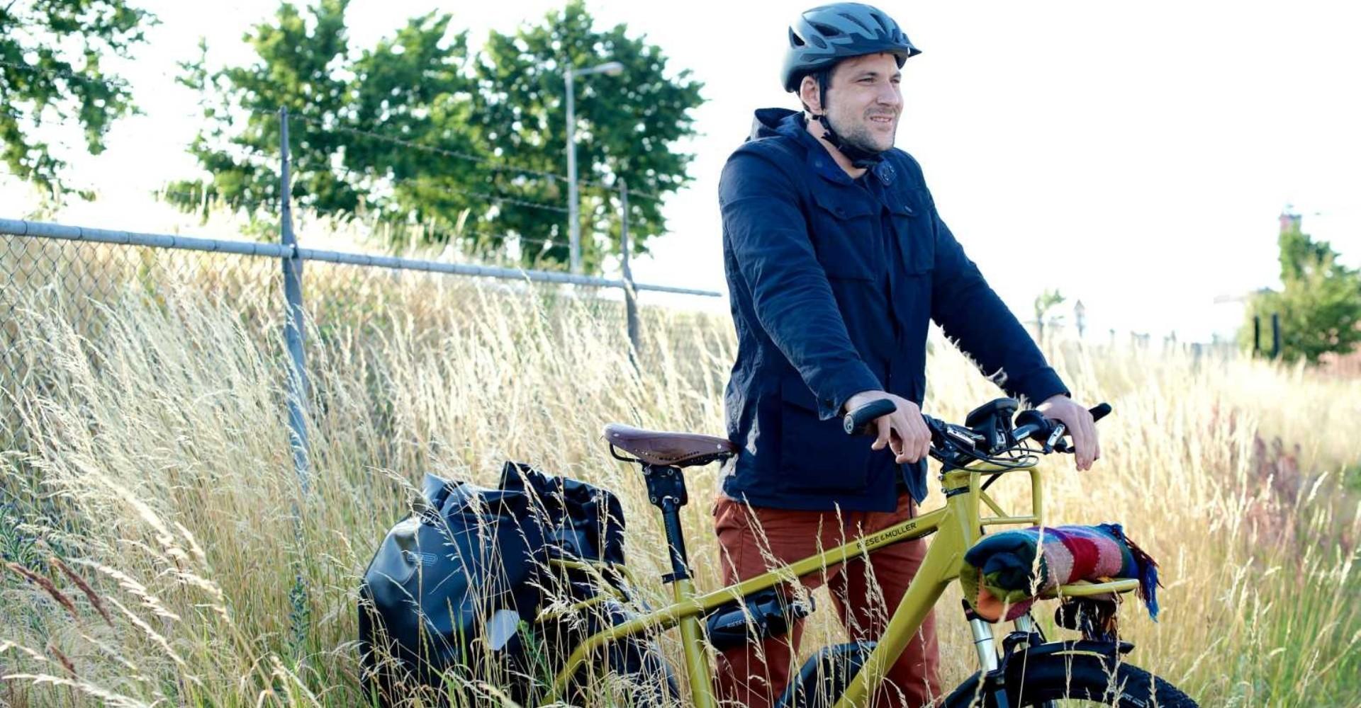 Mann steht im Feld mit dem e-Bike Riese & Müller Charger 2015