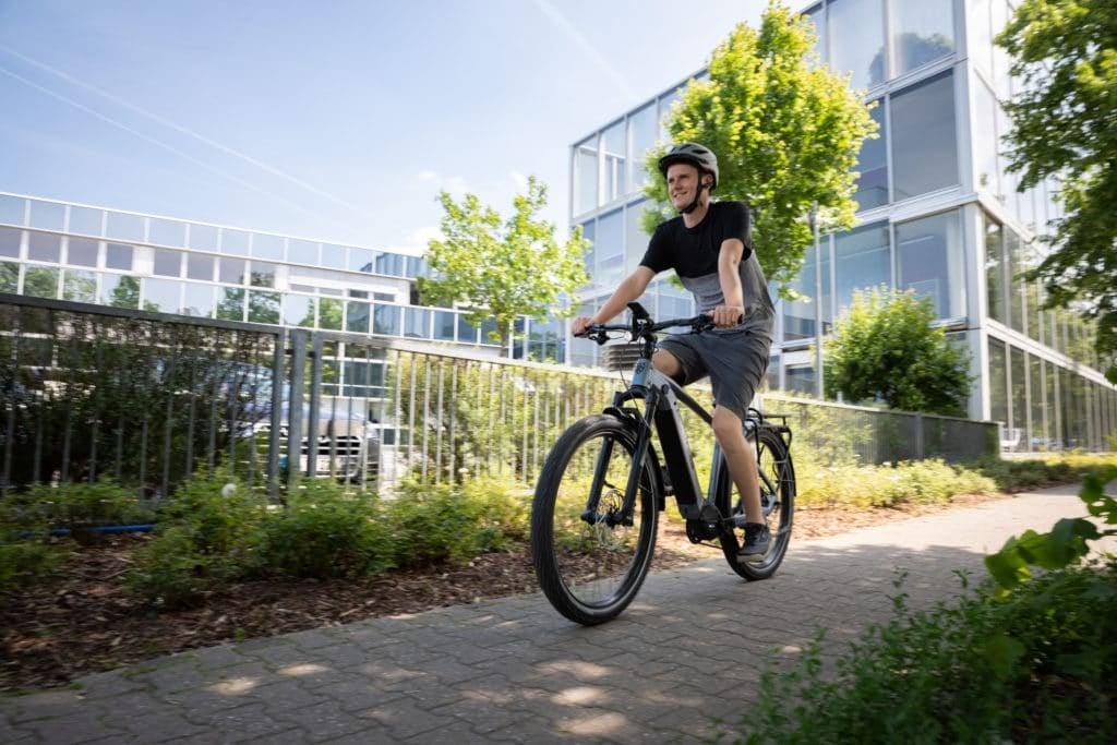 Mann fährt Hercules E-Bike SUV vor modernen Gebäuden