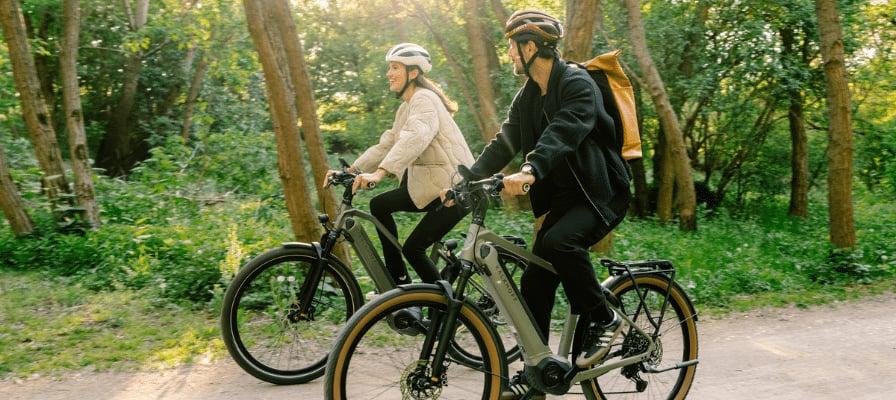 Zwei Radfahrer auf E-Bikes im Wald bei sonnigem Wetter