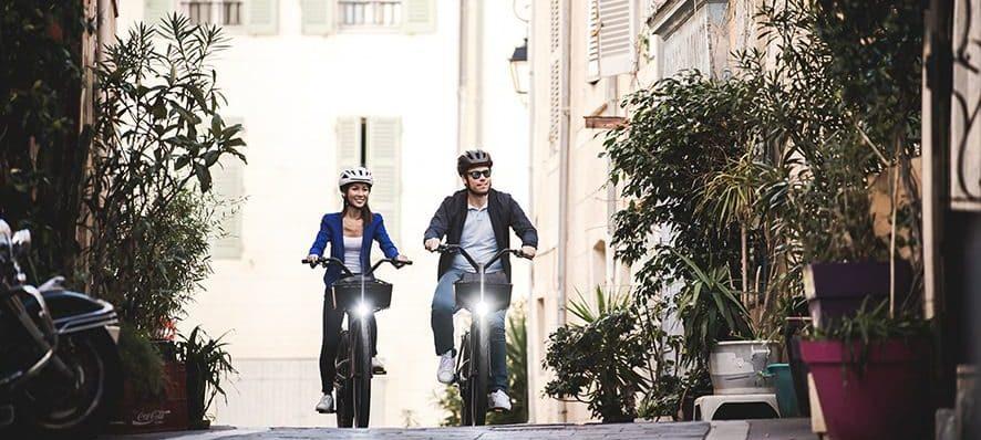 Eine Frau und ein Mann fahren auf einem Specialzed e-Bike, umgeben von Pflanzen