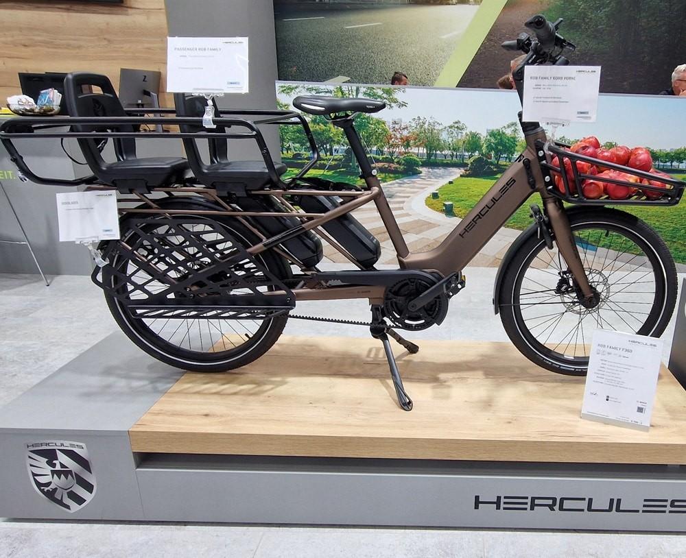 Hercules e-Bike in mattem Braun mit stabilem Rahmen, großem Gepäckträger und e-Antrieb, ausgestellt auf Podest.