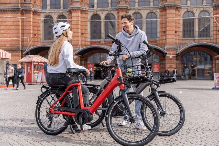 Zwei Personen mit Hercules E-Bikes vor historischem Gebäude