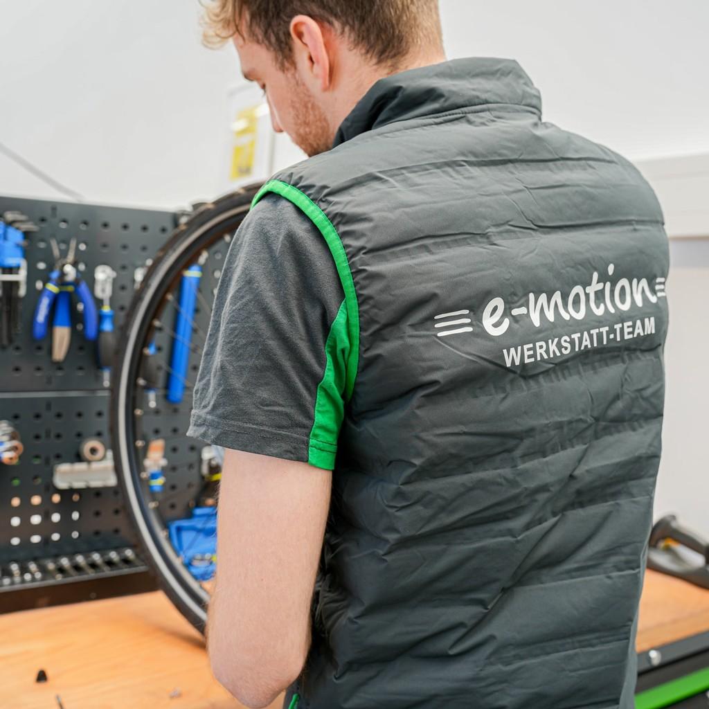 Ein Mitarbeiter des e-motion Werkstatt-Teams wartet ein Fahrrad in einer gut ausgestatteten Werkstatt mit professio