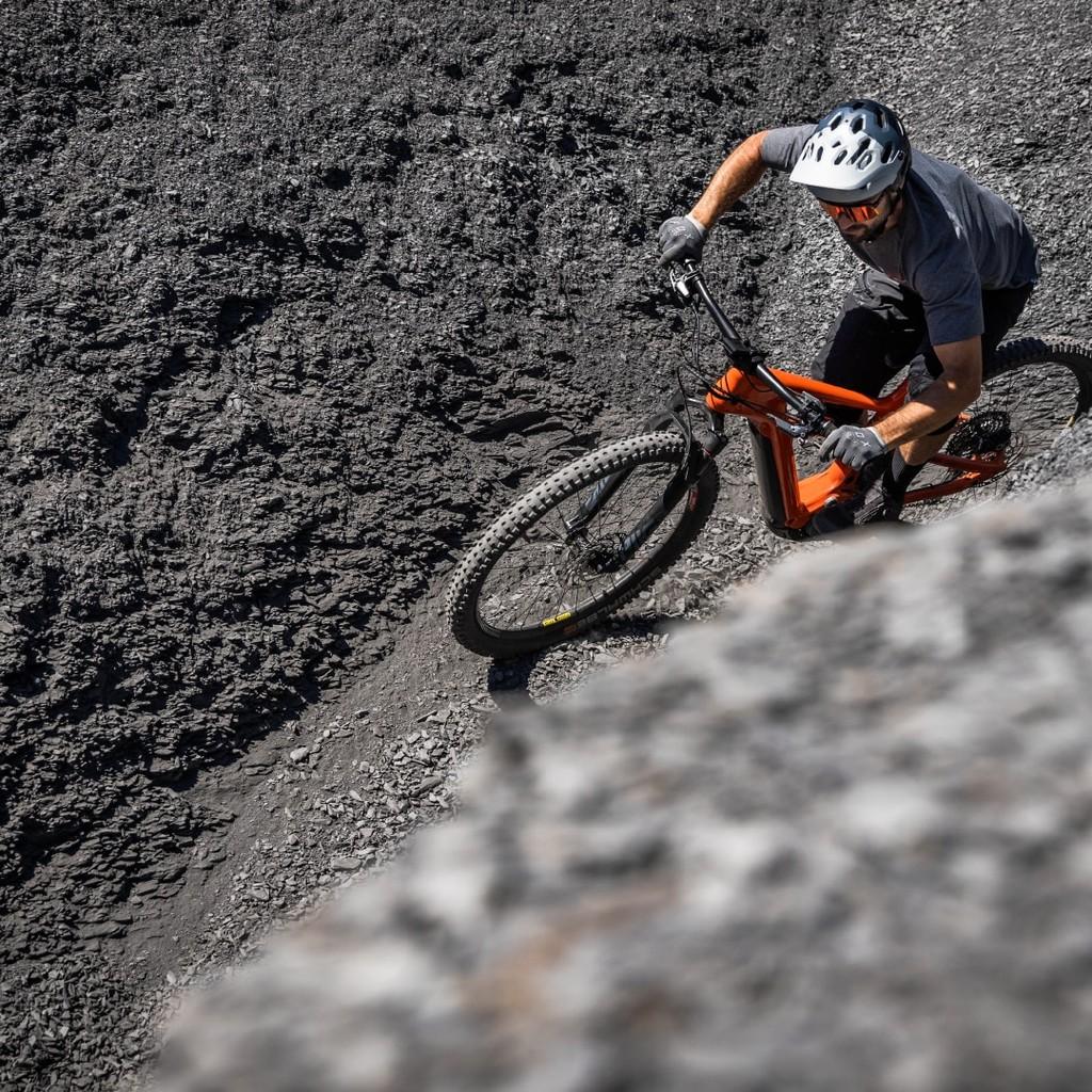 Ein e-Biker ist unterwegs auf sehr steinigem und hügeligem Untergrund