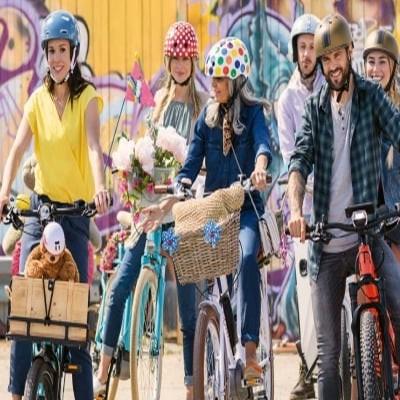 Gruppe von Menschen mit E-Bikes vor bunter Graffiti-Wand