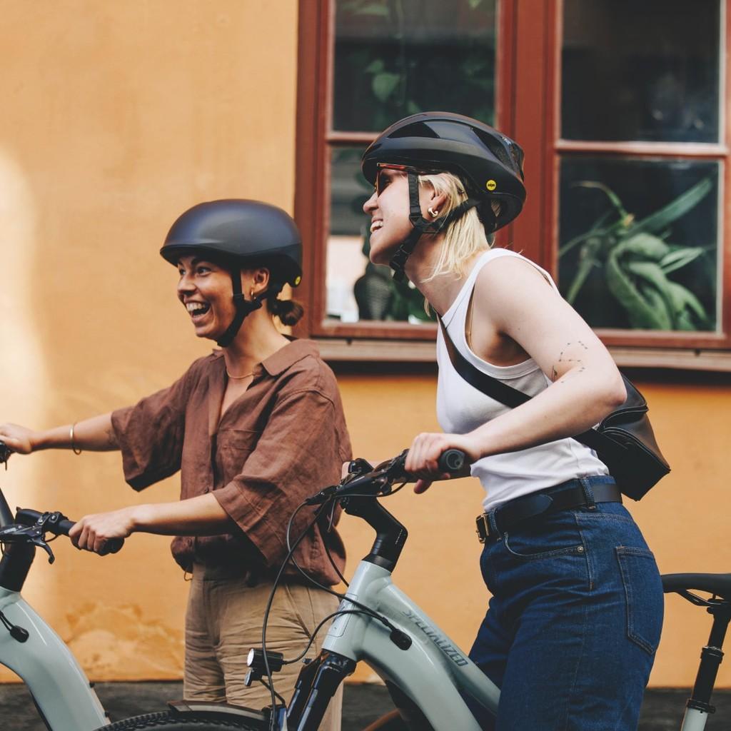 Zwei e-Bike Fahrerinnen schieben das Specialized Como Rad durch die Stadt