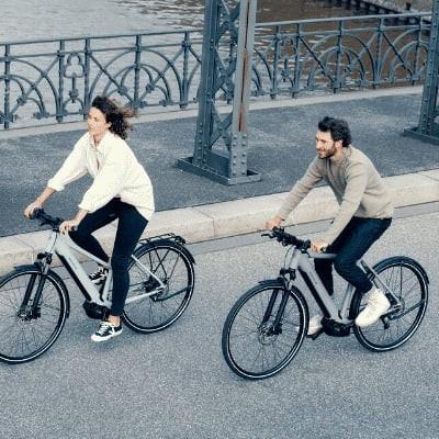 Zwei Personen fahren Riese & Müller E-Bikes auf einer Brücke