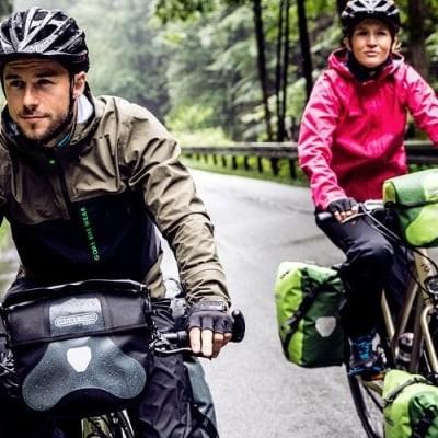 Zwei Radfahrer mit Ortlieb-Fahrradtaschen auf nasser Waldstraße