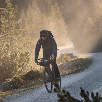 Radfahrer auf Schotterweg im Wald bei Sonnenuntergang