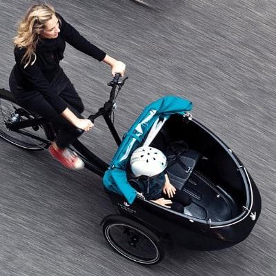 Frau fährt Lastenrad mit Kind durch die Stadt