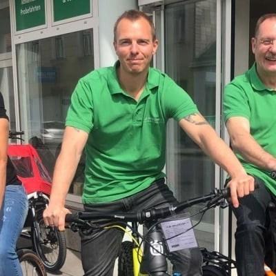 Drei Männer auf Fahrrädern vor einem Geschäft in Wien