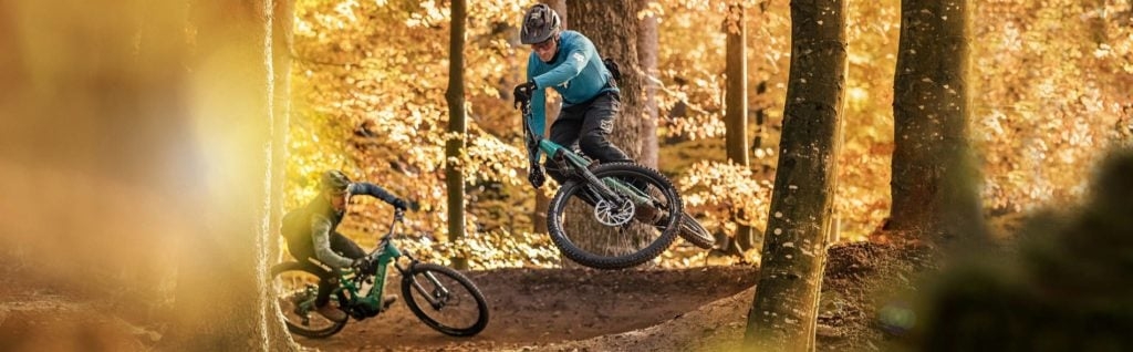 Zwei Mountainbiker auf Waldpfad bei Herbstlicht