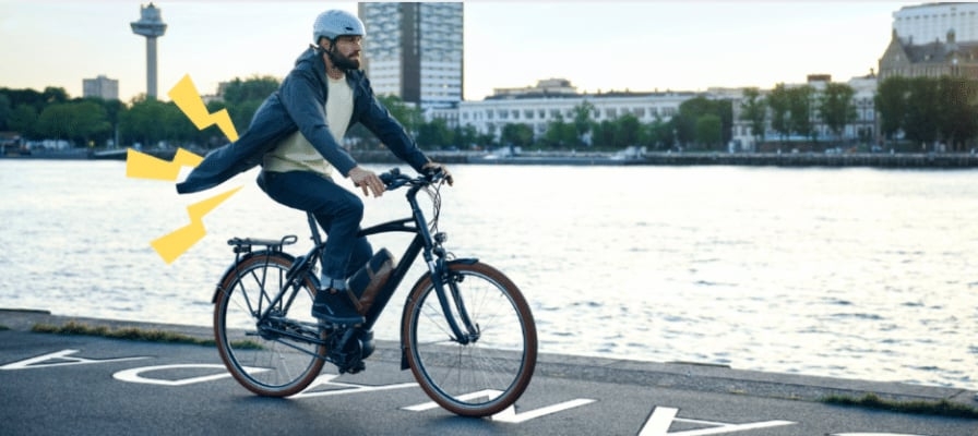 Mann auf E-Bike mit Fluss im Hintergrund bei Sonnenuntergang