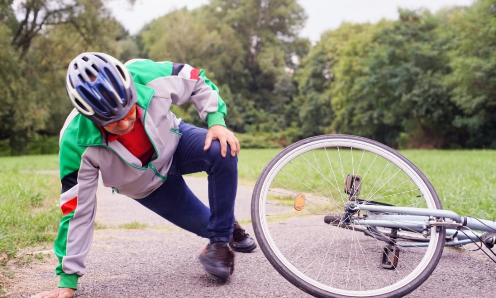 Ein Radfahrer ist auf einem Radweg gestürzt. Das Bild zeigt das liegende Fahrrad und den verletzten Fahrer in Schut