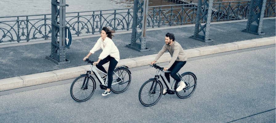 Zwei Personen fahren Riese & Müller E-Bikes auf einer Brücke