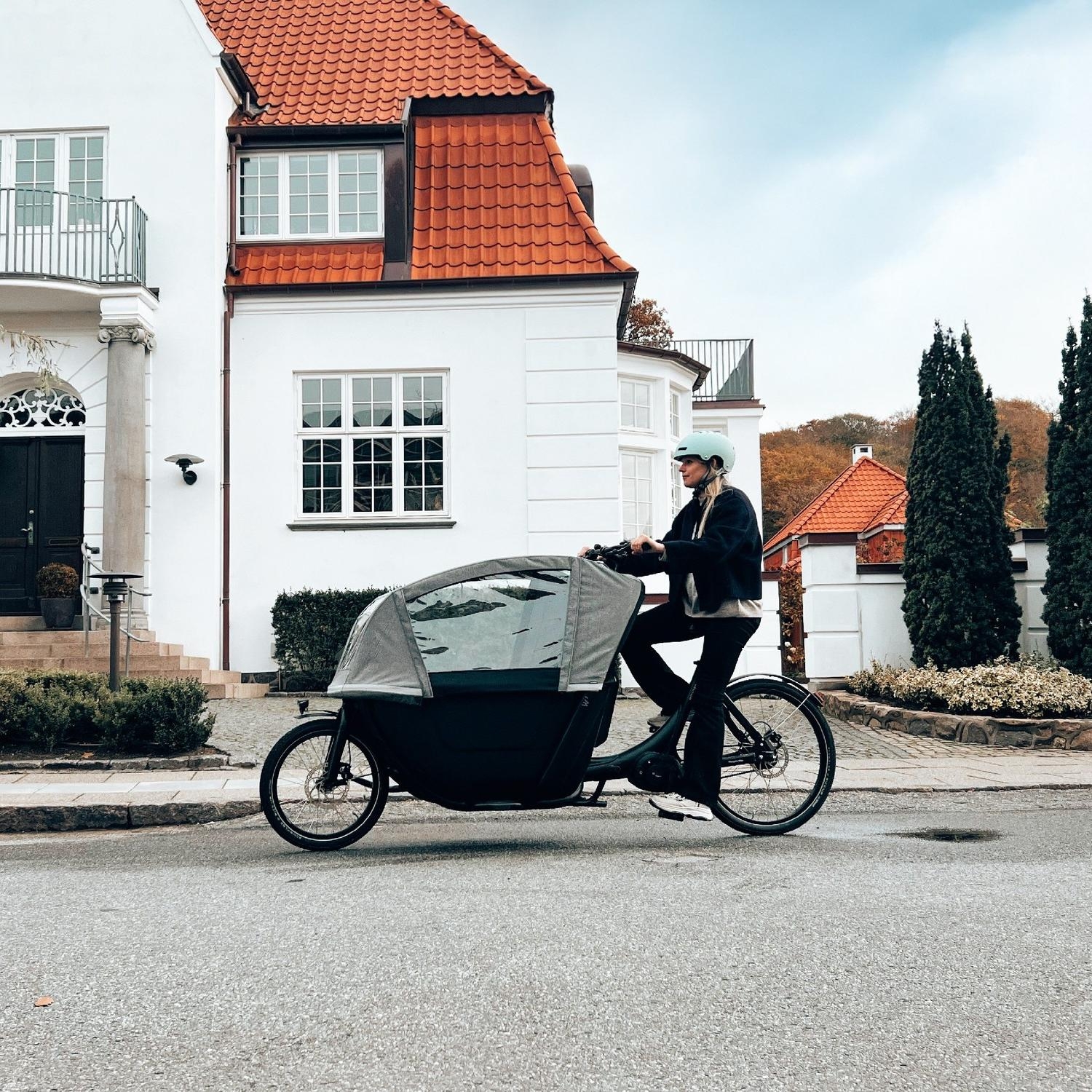Eine Frau fährt mit dem neuen Winther W2 Lasten e-Bike durch ein Wohngebiet.