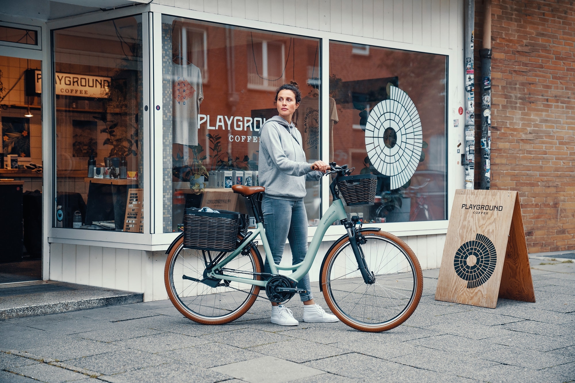 Entdecke das stilvolle RM_MY2022 E-Bike. Perfekt für urbane Abenteuer, gezeigt vor dem Playground Coffee. Komfort u