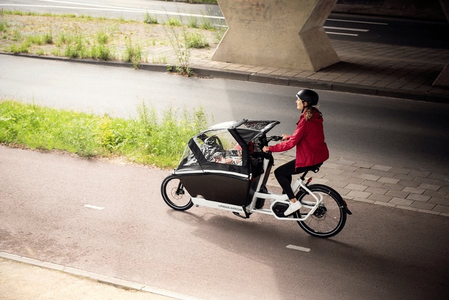 Person fährt Urban Arrow Lastenrad auf Radweg