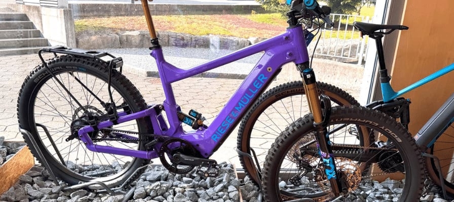 Lila Riese & Müller E-Bike vor Gebäude auf Schotter