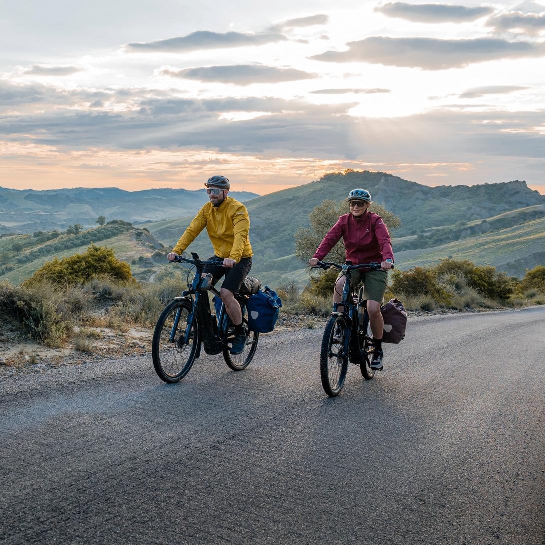 Zwei Personen fahren auf e-Bikes mit Bosch PX Antrieb durch malerische Kulissen